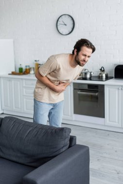 Man suffering from stomachache in kitchen  clipart