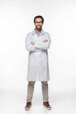 Kollarını kavuşturmuş gülümseyen doktor beyaz arka plandaki kameraya bakıyor. 