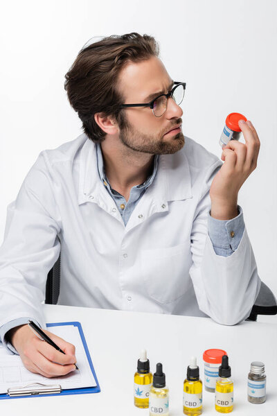 врач выписывает рецепт, держа медикаменты каннабиса изолированы на белом