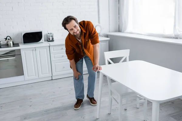 Man Frowning Touching Knee While Suffering Pain Kitchen — Stock Photo, Image