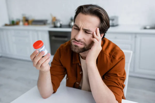 Frowning Man Looking Container Medical Cannabis While Suffering Pain Kitchen — Stock Photo, Image