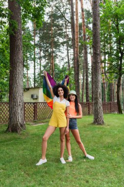 Parkta lgbt bayrağı taşıyan neşeli ırklar arası kadınlar 