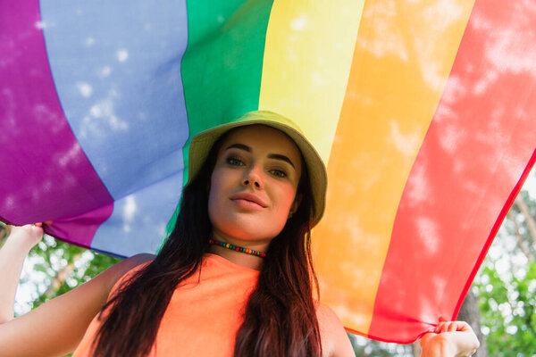 Low angle view of young woman holding lgbt flag outdoors 