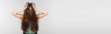 young woman adjusting tangled long hair isolated on grey, banner clipart