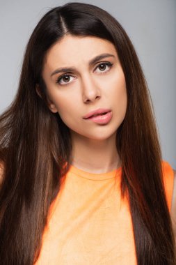 Düşünceli genç bir kadın dudak ısırıyor ve gri renkli kameraya bakıyor.