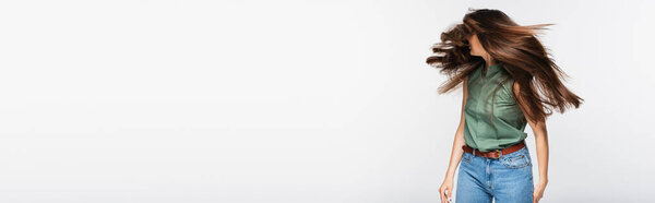 молодая женщина с блестящими волосами покачивая головой изолированы на сером, баннер