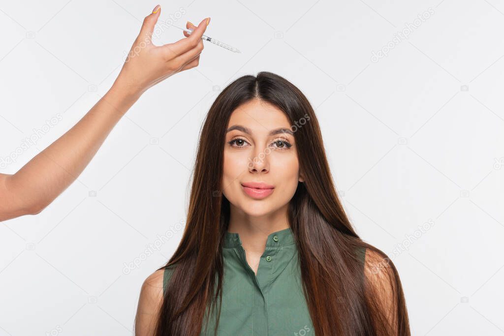 beautician holding syringe with cosmetic filler near hair of woman isolated on grey