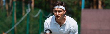 Odaklanmış tenis oyuncusu, raketi sahada duruyor, afiş. 