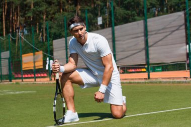 Mahkemede diz çökerken raket tutan odaklanmış sporcu. 