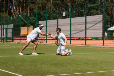 Heyecanlı çok ırklı tenis oyuncuları sahada el sıkışıyor 