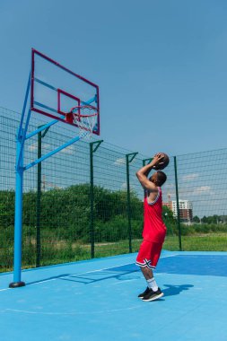Basketbol sahasında topu çemberin altında tutan Afrikalı Amerikalı oyuncunun yan görünüşü 