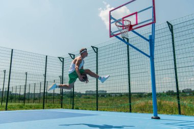 Açık hava çocuk parkında sokak basketbolu oynayan sporcunun yan görünümü 
