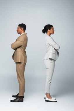 side view of african american business people standing separately with crossed arms on grey, gender equality concept clipart