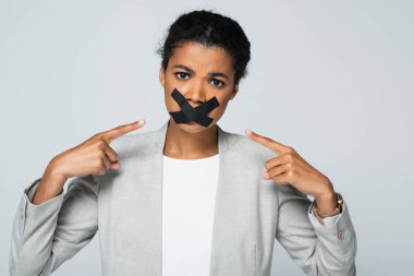 Afrikalı Amerikalı iş kadını, Grey 'de izole edilmiş ağız bandına işaret ediyor.