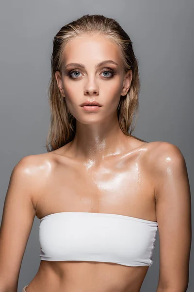 wet woman in white top looking at camera isolated on grey