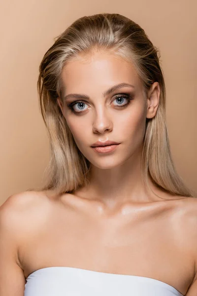 young woman with perfect face and makeup looking at camera isolated on beige