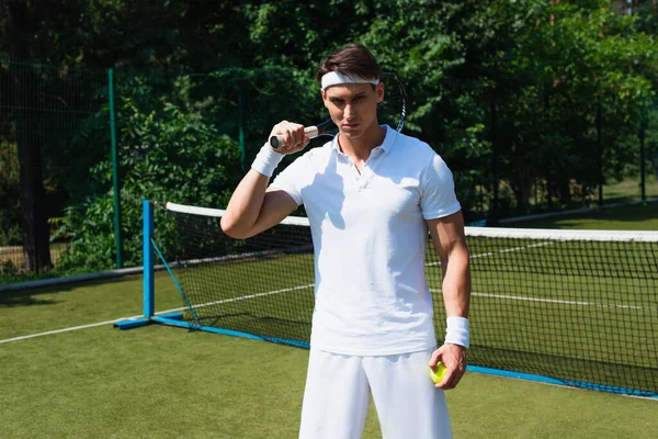身穿白色运动服的年轻运动员在网球场上拿着球拍和球 — 图库照片