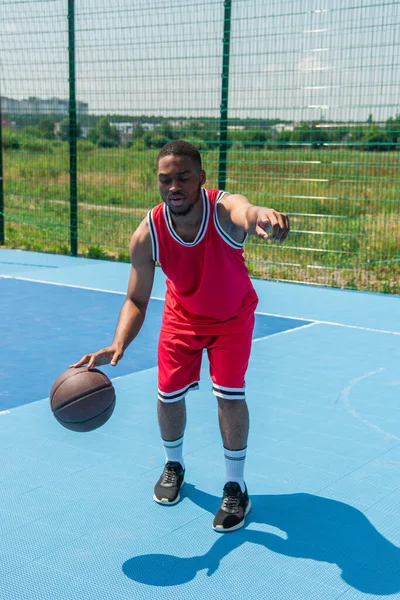 African american man pointing with finger while playing streetball on playground