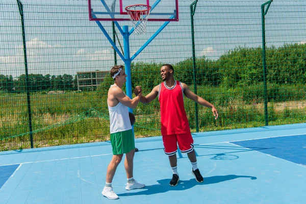 Uśmiechnięci Wielonarodowi Sportowcy Ściskający Dłonie Boisku Streetballa — Zdjęcie stockowe