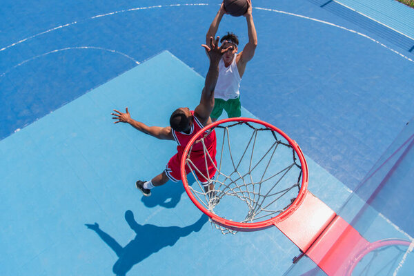 Overhead view of multiethnic sportsmen playing streetball on playground 