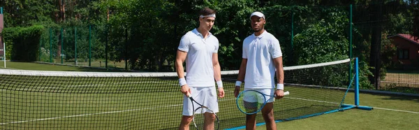 身穿白色运动服的多族裔网球选手手持球拍 — 图库照片