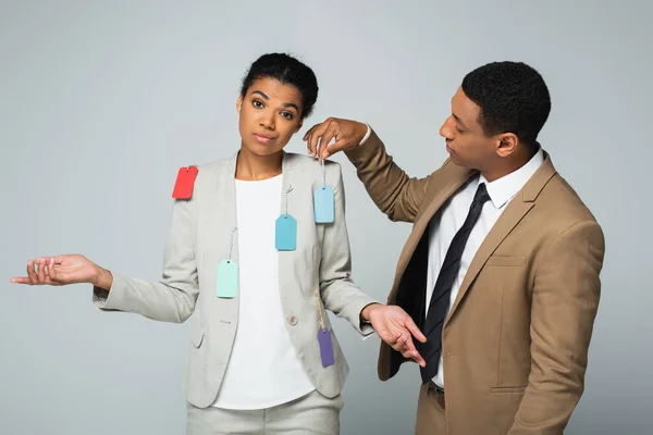 Hombre Negocios Afroamericano Colgando Etiquetas Mujer Negocios Mostrando Gesto Encogimiento — Foto de Stock