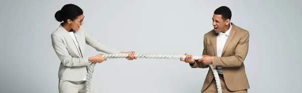 businessman and businesswoman pulling rope isolated on grey, banner