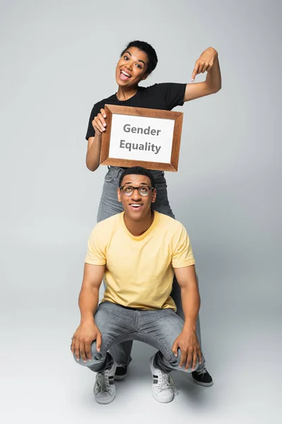 若いアフリカ系アメリカ人の女性が男性の近くでジェンダー平等のレタリングをし — ストック写真