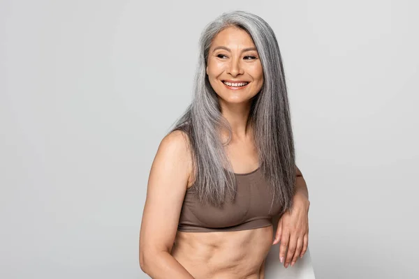 Positivo Asiatico Donna Reggiseno Guardando Lontano Sedia Isolato Grigio — Foto Stock