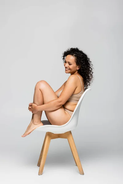 Sorrindo Mulher Americana Africana Roupa Interior Sentado Cadeira Fundo Cinza — Fotografia de Stock