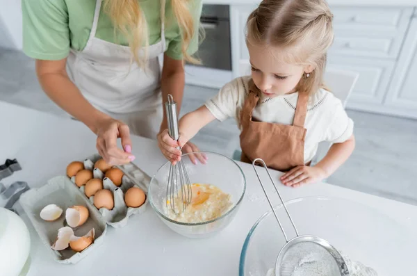 Menina Avental Misturando Ovos Farinha Tigela Perto Mãe Cozinha — Fotografia de Stock