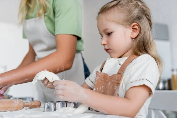 Niño Sosteniendo Masa Cerca Cortadores Galletas Mamá Borrosa Cocina — Foto de Stock