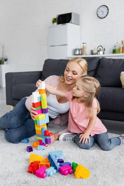 Mädchen Bastelt Turm Aus Bunten Bauklötzen Nahe Der Glücklichen Mutter — Stockfoto