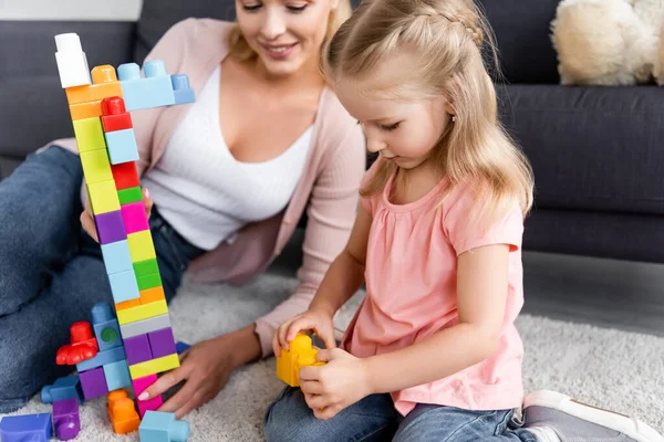 Dziecko Bawiąc Się Klocków Pobliżu Rozmyte Mama Domu — Zdjęcie stockowe