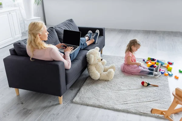 Woman Typing Laptop Sofa Daughter Playing Building Blocks Floor — Stock Photo, Image