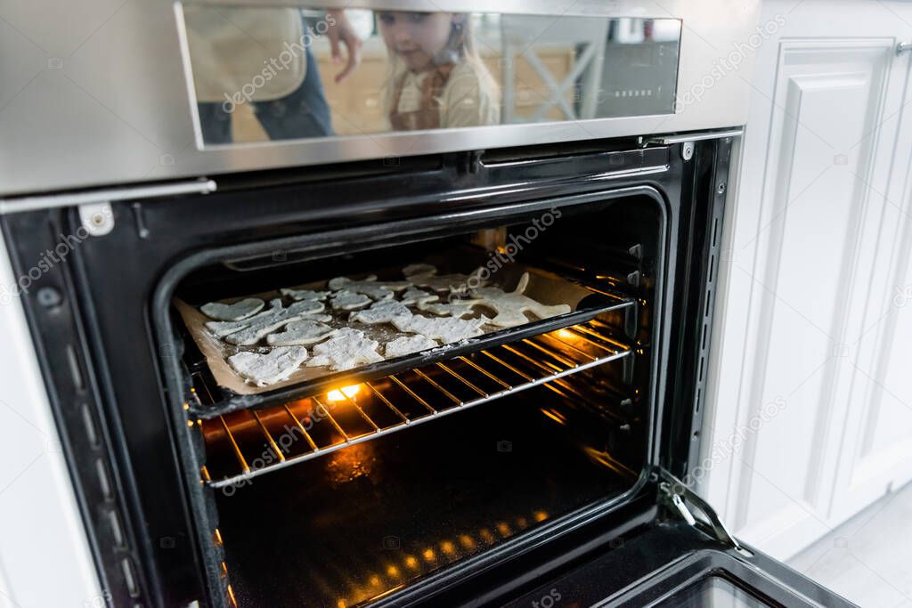 baking sheet with multi shaped cookies in electric oven