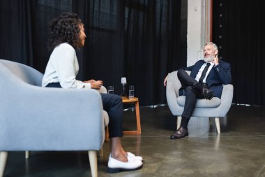 Bulanık Afrikalı Amerikalı gazeteci talk show sırasında gülümsüyor ve iş adamıyla konuşuyor. 