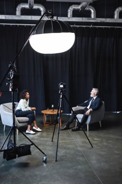 Afrikalı Amerikalı gazeteci iş adamıyla röportaj stüdyosunda konuşuyor. 