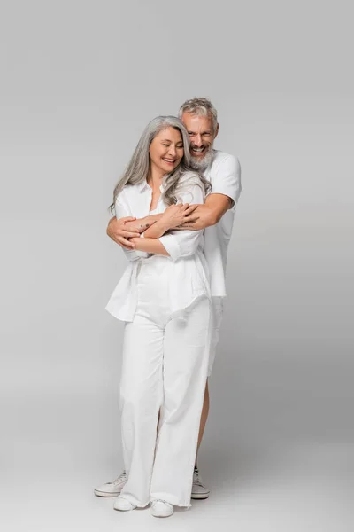 Volledige Lengte Van Liefdevolle Interraciale Volwassen Paar Knuffelen Glimlachen Grijs — Stockfoto