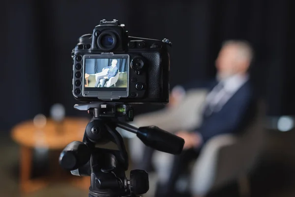 digital camera with businessman in suit during interview on screen