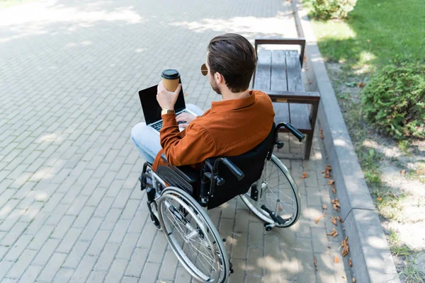 Mozgássérült Férfi Tolószékben Tartja Kávé Menni Miközben Gépel Laptop Szabadban — Stock Fotó