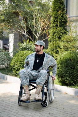 Tekerlekli sandalyedeki özürlü asker dışarı bakarken gülümsüyor.