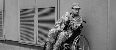 Tekerlekli sandalyede oturan engelli genç asker. Elinde bir şişe alkol, afiş.
