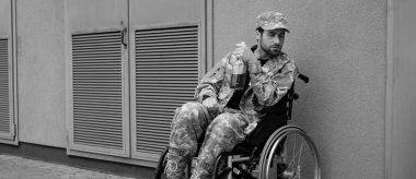 young disabled soldier sitting in wheelchair with bottle of alcohol outdoors, banner clipart