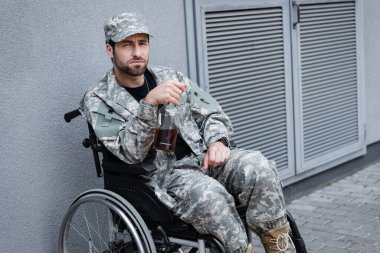 depressed and disabled military man sitting in wheelchair with bottle of alcohol clipart