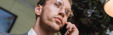 Kafede akıllı telefondan konuşan genç işadamının düşük açılı görüntüsü, afiş.