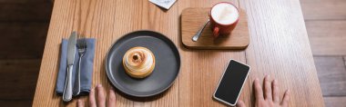 Limonlu tart, cappuccino ve üzerinde boş ekran ve afiş olan akıllı telefonun yüksek açılı görüntüsü