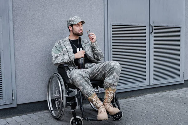 坐在轮椅上抽烟和在户外拿着酒瓶的残疾老兵 — 图库照片