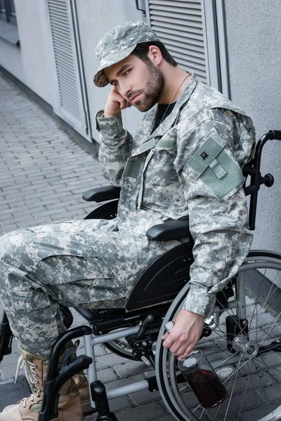 坐在轮椅上的伤残士兵坐在城市街道上看着相机 — 图库照片