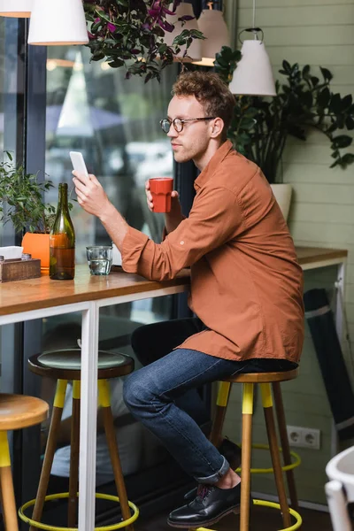 Young Man Glasses Holding Cup Using Smartphone Cafe — Stock Photo, Image